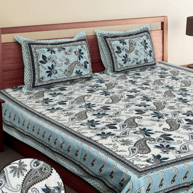 Bed with floral patterned bedspread and pillows in a bedroom setting.