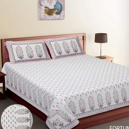 Bed with floral patterned bedspread and pillows in a bedroom setting. RESTEZZY